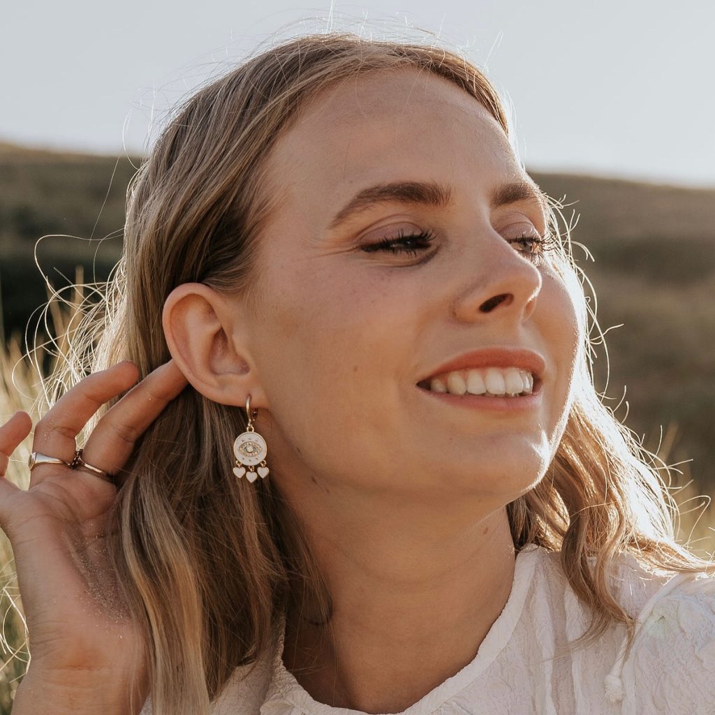 Model wears Wisteria London Amaya Evil Eye Huggie Hoop Earrings